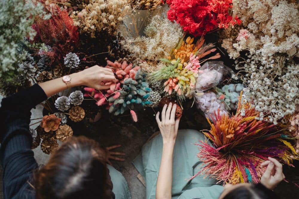 crop faceless florists touching decorative bouquet elements and flowers