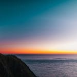 sunset sky over sea and lighthouse located on hill