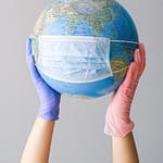 hands with latex gloves holding a globe with a face mask