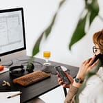 busy female talking on smartphone and checking messages during work in contemporary office