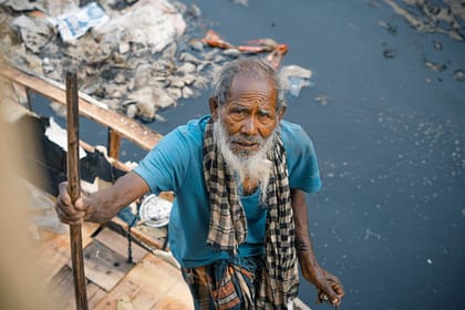 elderly ethnic man near dirty river