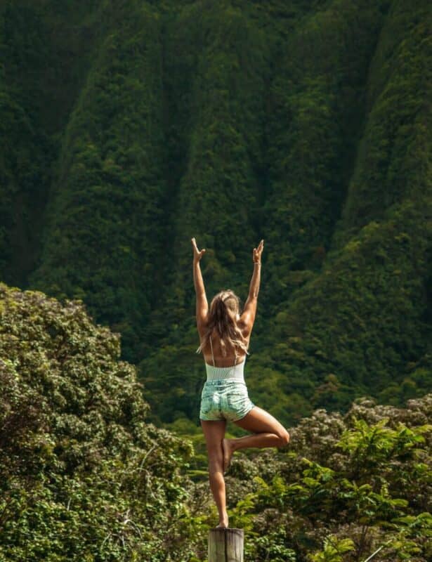 anonymous woman standing in vrksasana pose while practicing yoga in nature