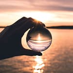 photo displays person holding ball with reflection of horizon