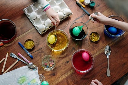 people holding silver spoons with colored eggs